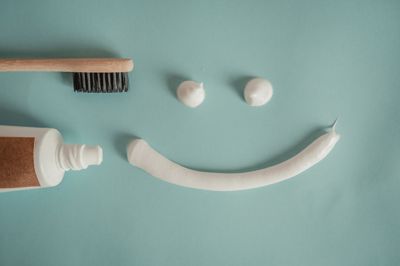 A playful arrangement of toothpaste and toothbrush forming a smile on a blue background.